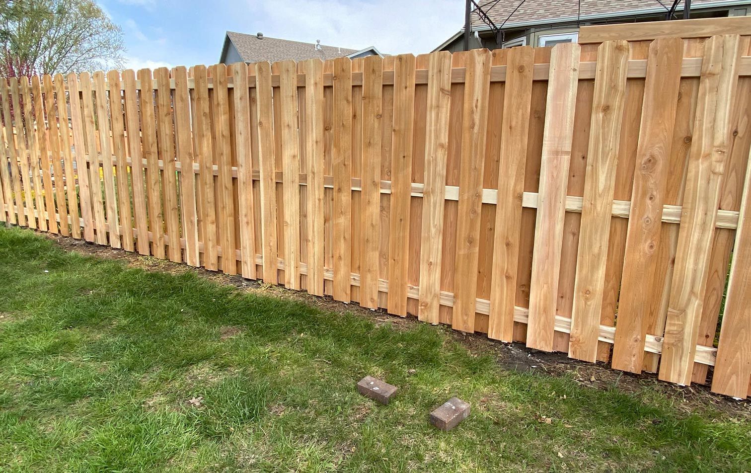 A wooden fence is sitting in the middle of a lush green yard.
