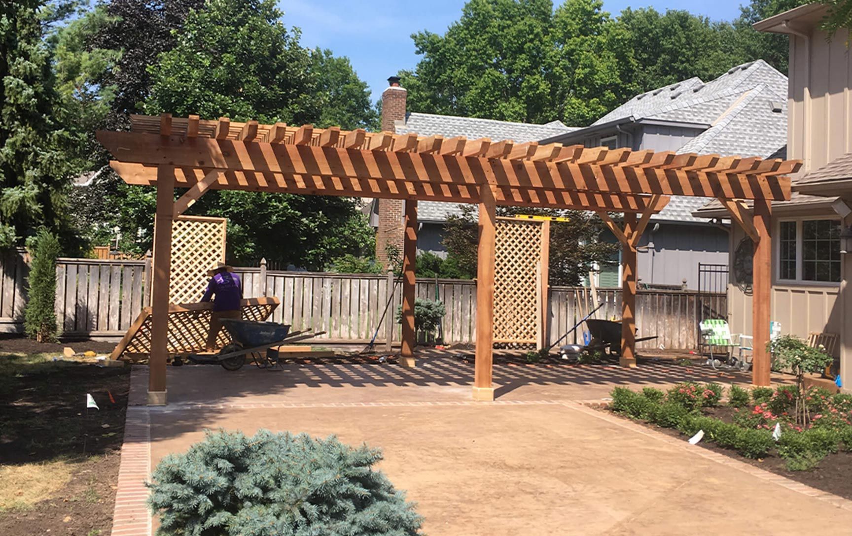 A wooden pergola is being built in the backyard of a house.