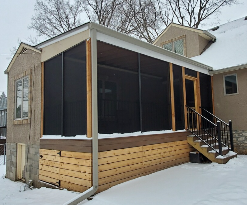 A wooden deck with a fence and trees in the background