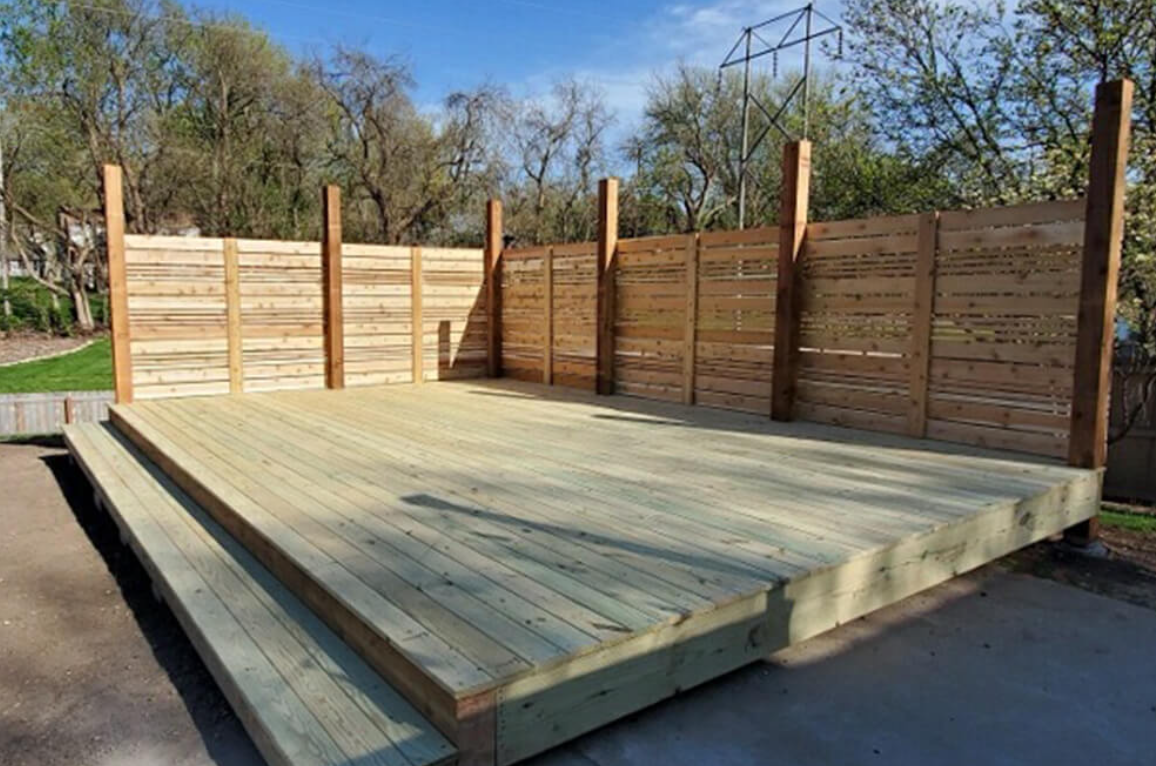 A wooden deck sits next to a swimming pool.
