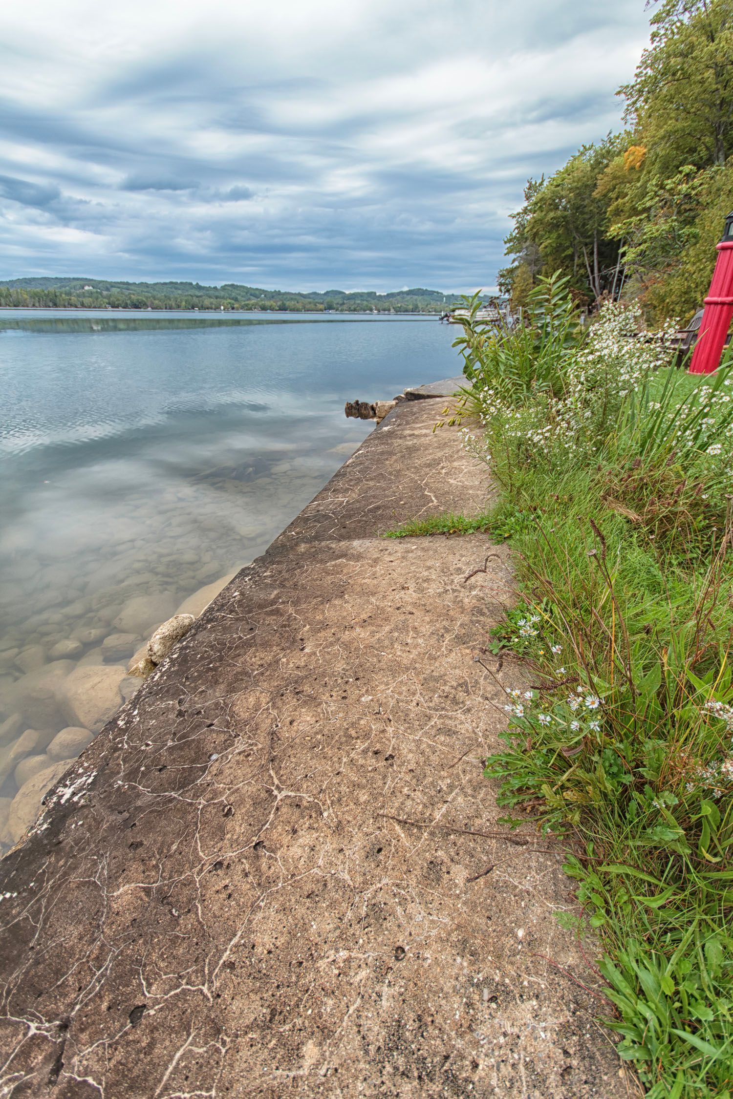 A red kayak is sitting on the shore of a lake
