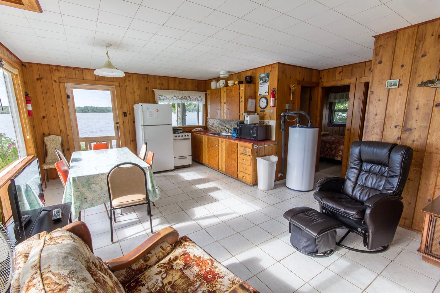 A living room with a couch , chair , table and refrigerator