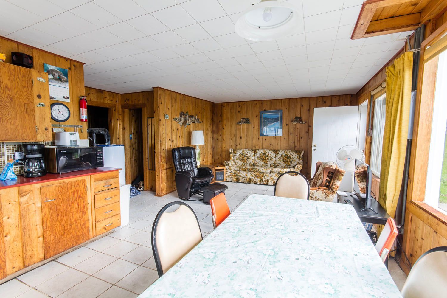 A living room with a table , chairs , a couch and a kitchen