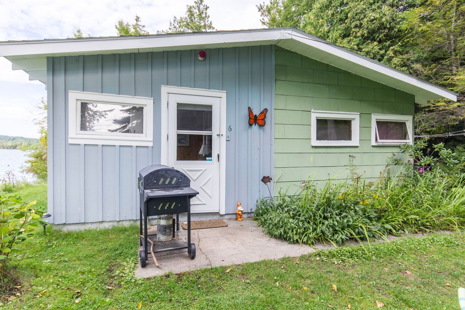 A small house with a grill in front of it and a butterfly on the door