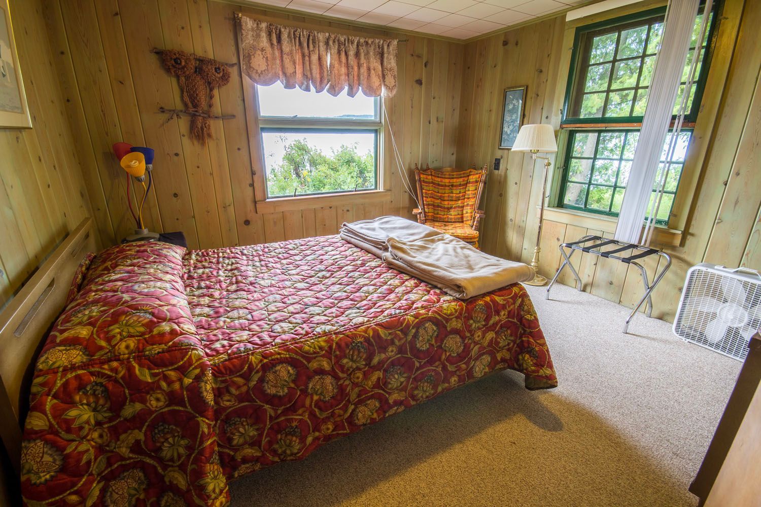 A bedroom with a bed , chair , lamp and window