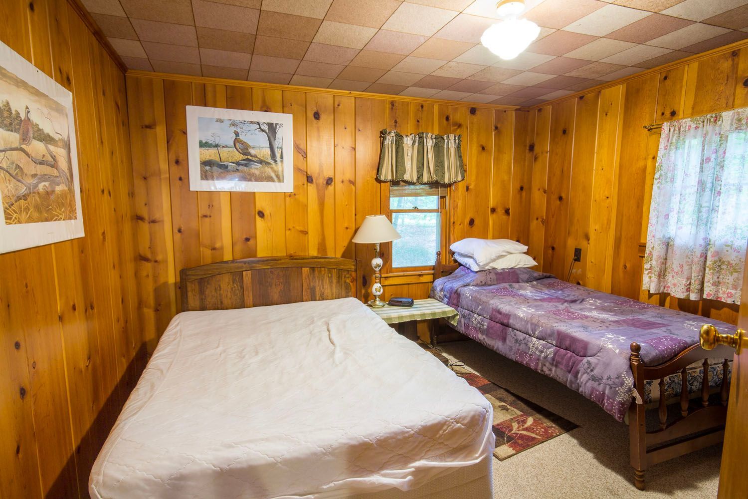 There are two beds in the room with wood paneling