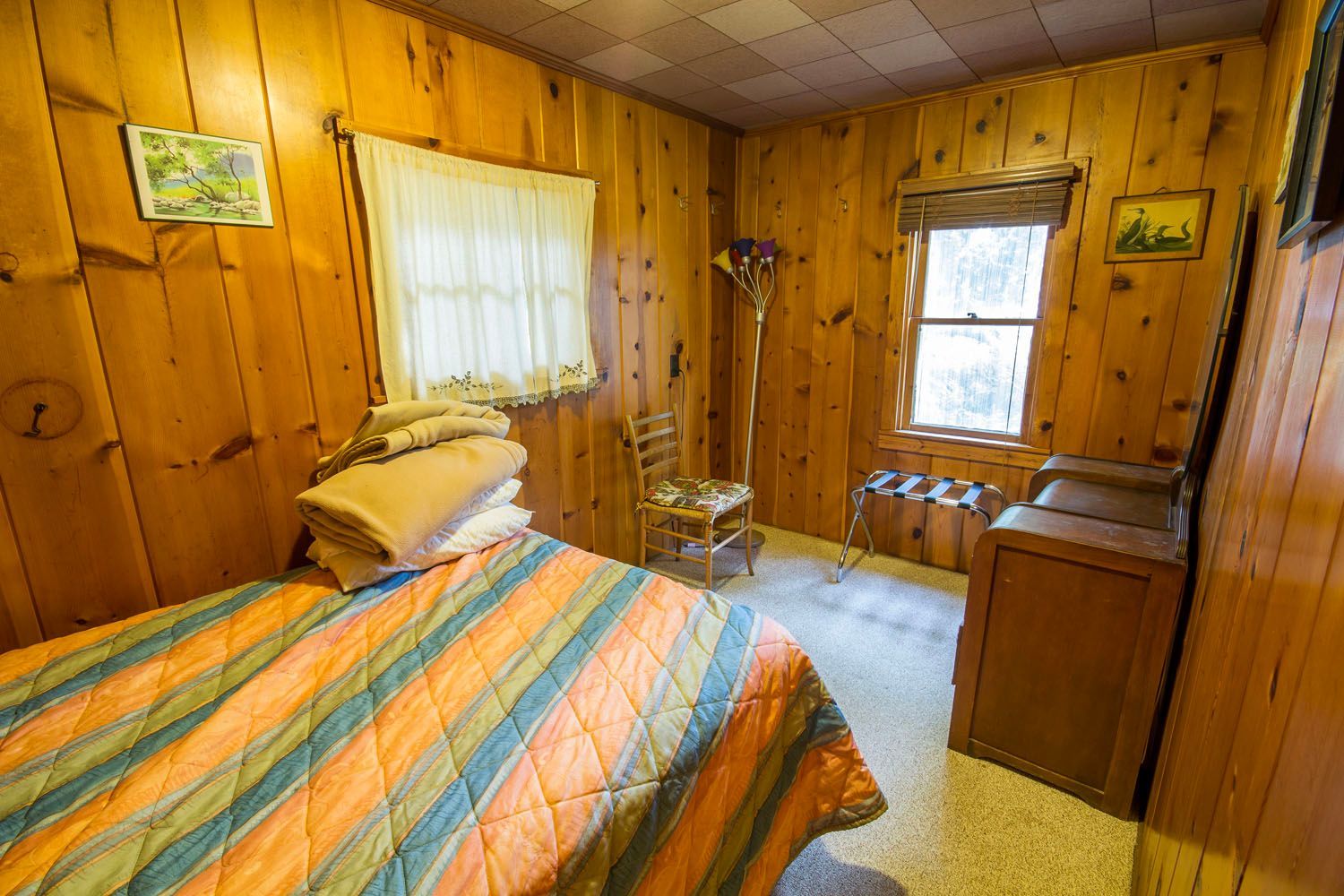 A bedroom with a bed , chair , dresser and window