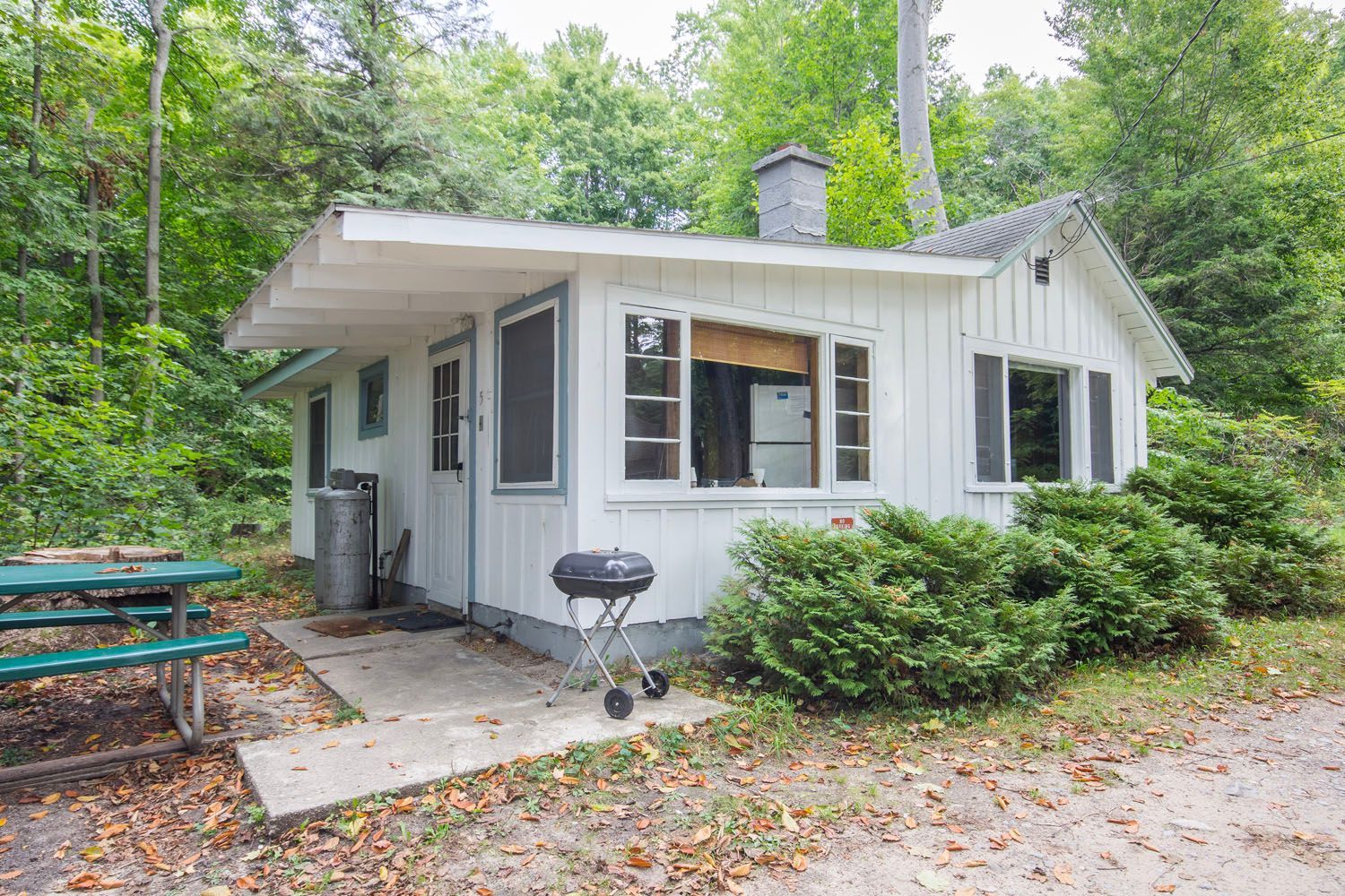 A small white house with a picnic table and grill in front of it