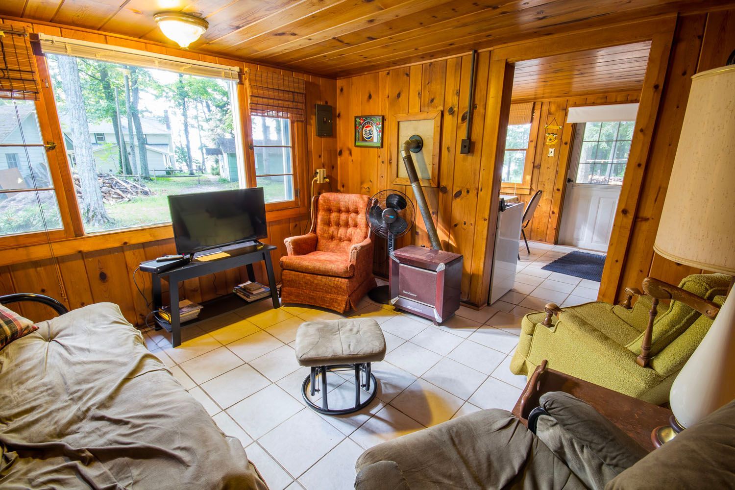A living room with a couch , chairs , a television and a fan