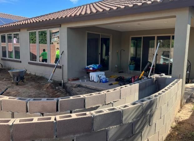 A brick wall is being built in front of a house.