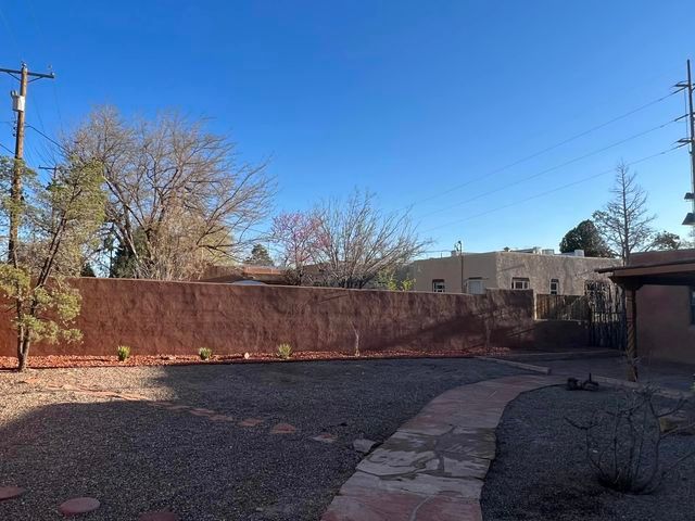 A backyard with a fence and a walkway leading to it