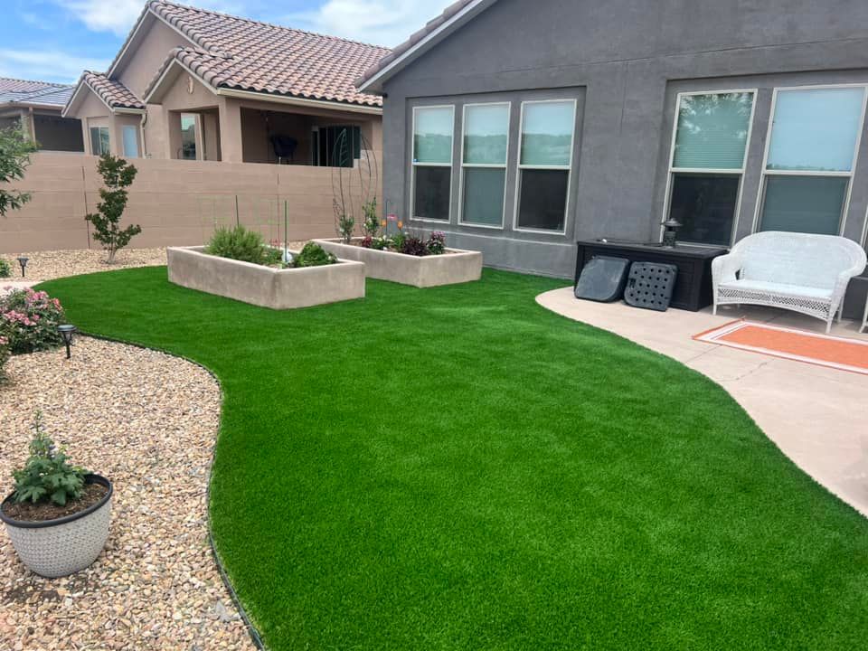 A lawn with a couch and chairs in front of a house.