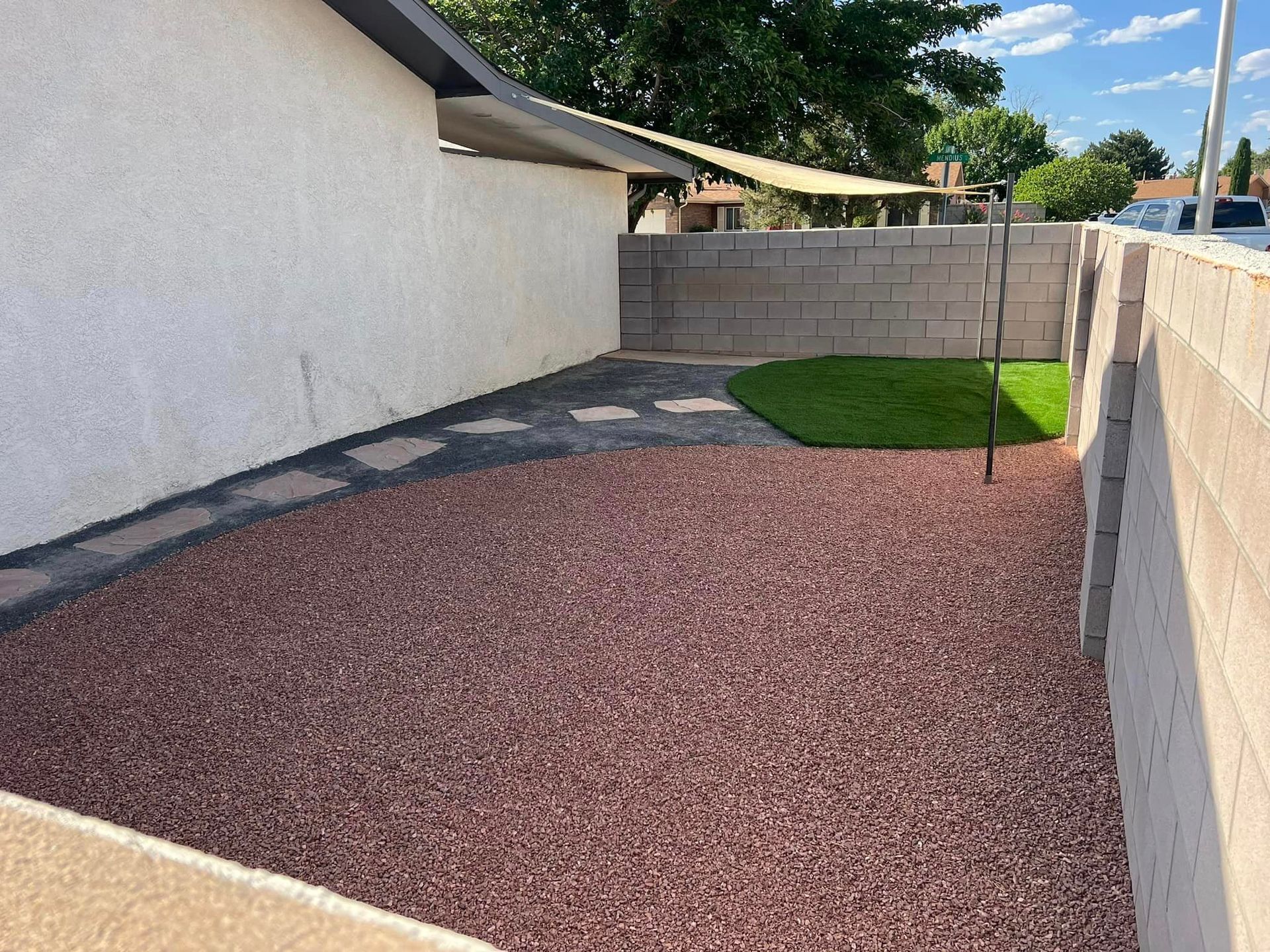 A gravel area in front of a house with a brick wall