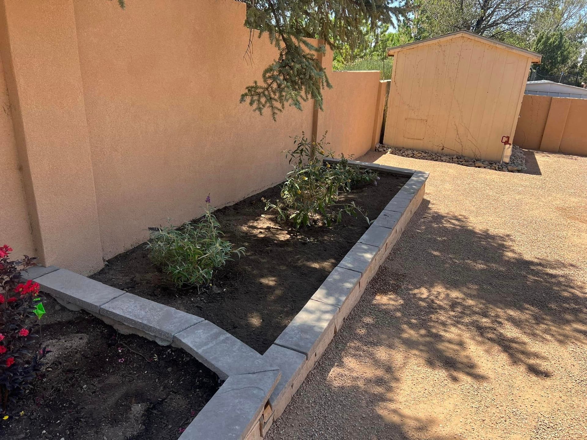 A concrete planter with plants in it in front of a house.