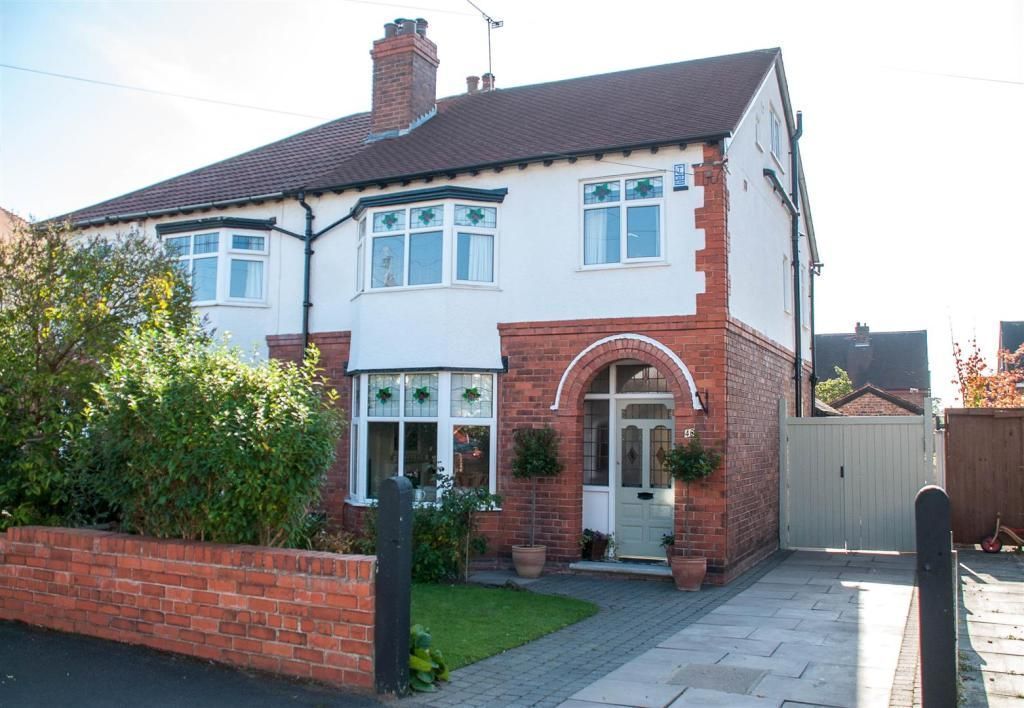 Two-story brick and white house with arched doorway and a driveway.