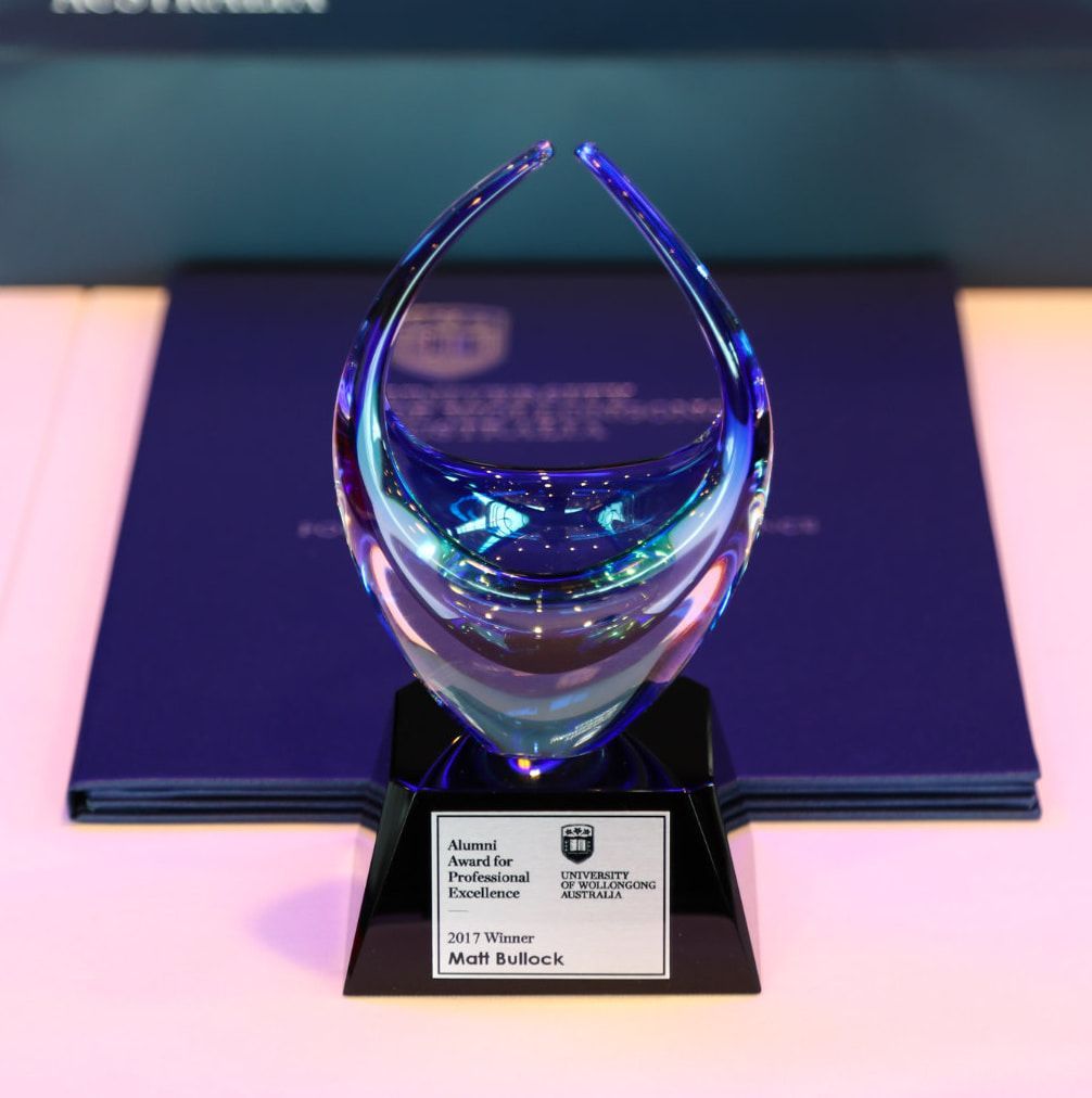 A Blue Glass Trophy Sitting on Top of a Purple Book — NMTG Engraving in Wollongong, NSW
