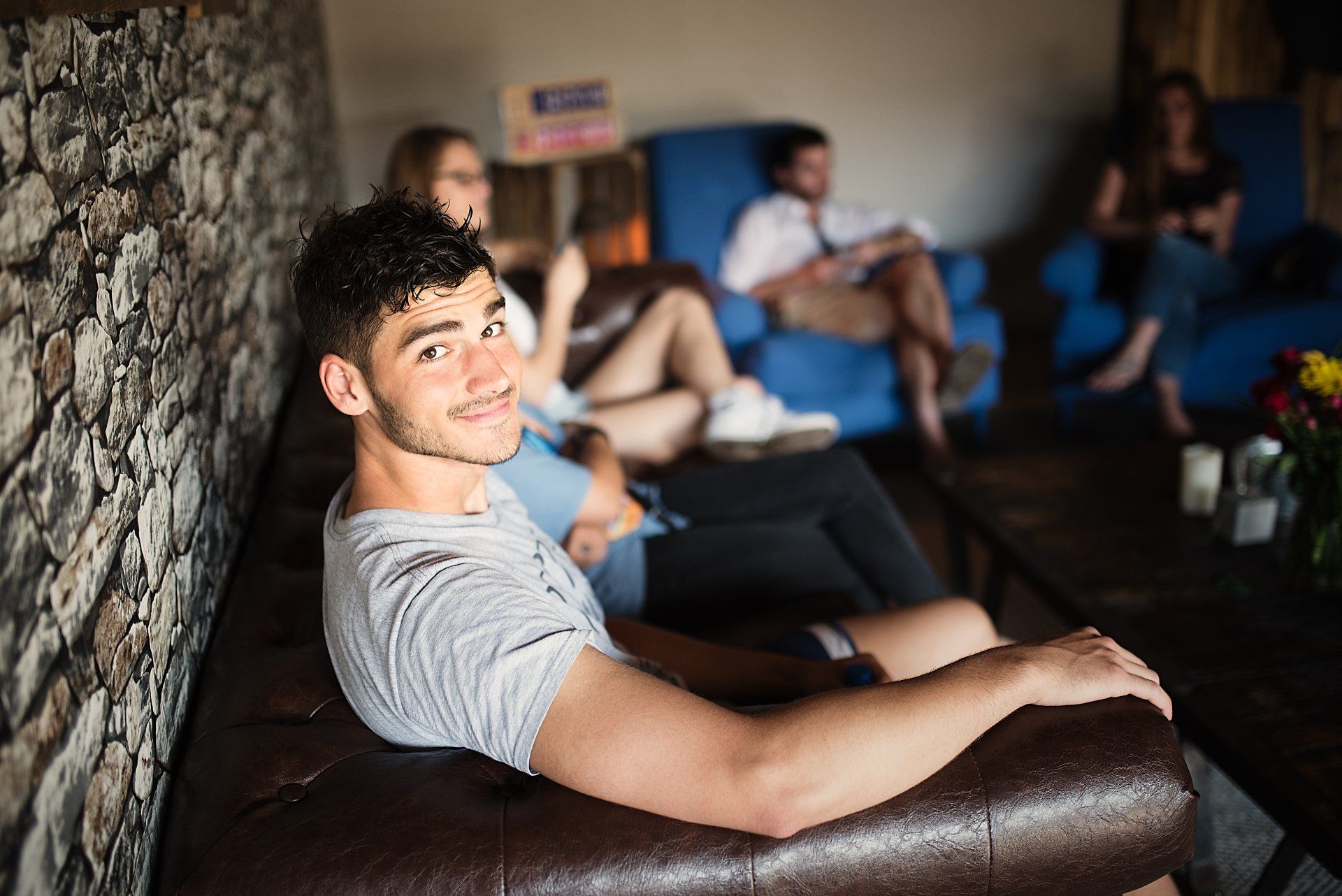 A man is sitting on a couch in a living room with other people.