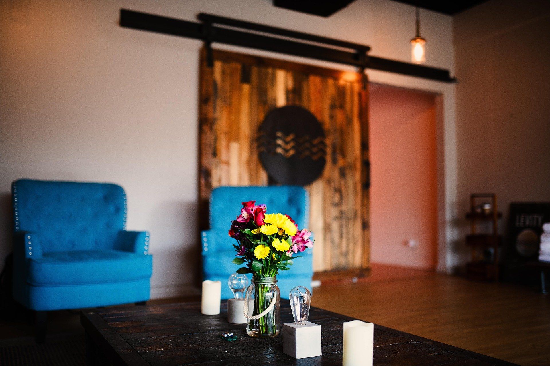 A living room with blue chairs and a table with flowers and candles on it.