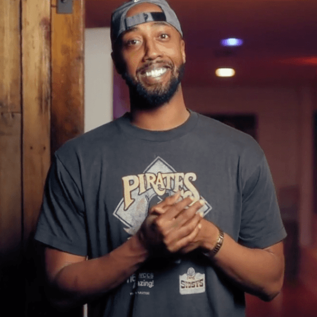 A man wearing a pirates t-shirt smiles for the camera