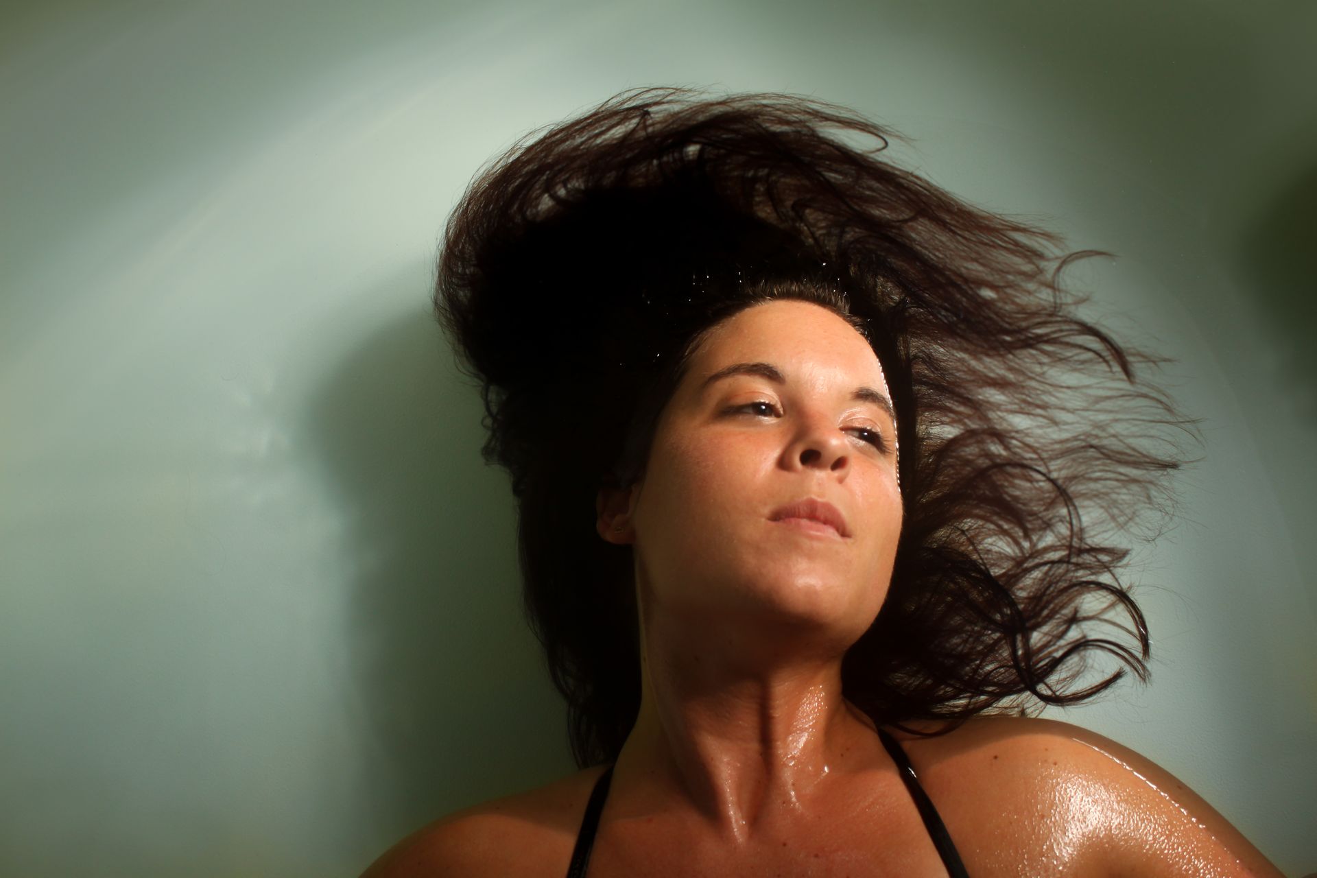A woman is floating in a bathtub with her hair blowing in the wind.