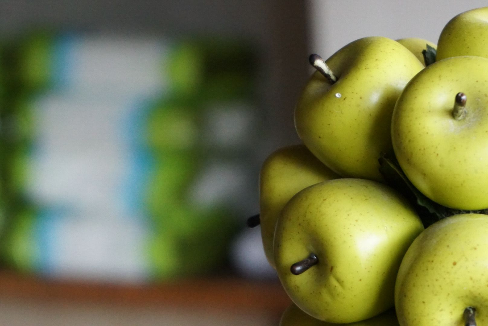 A bunch of green apples are stacked on top of each other on a table.