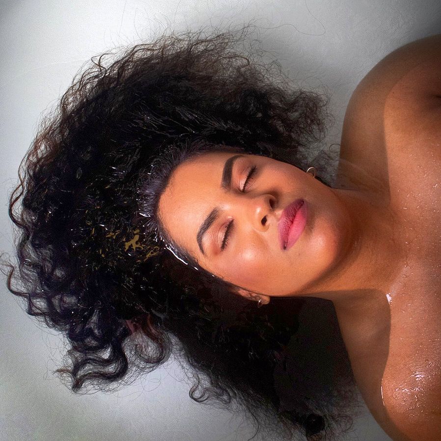 A woman laying in a bathtub with her eyes closed