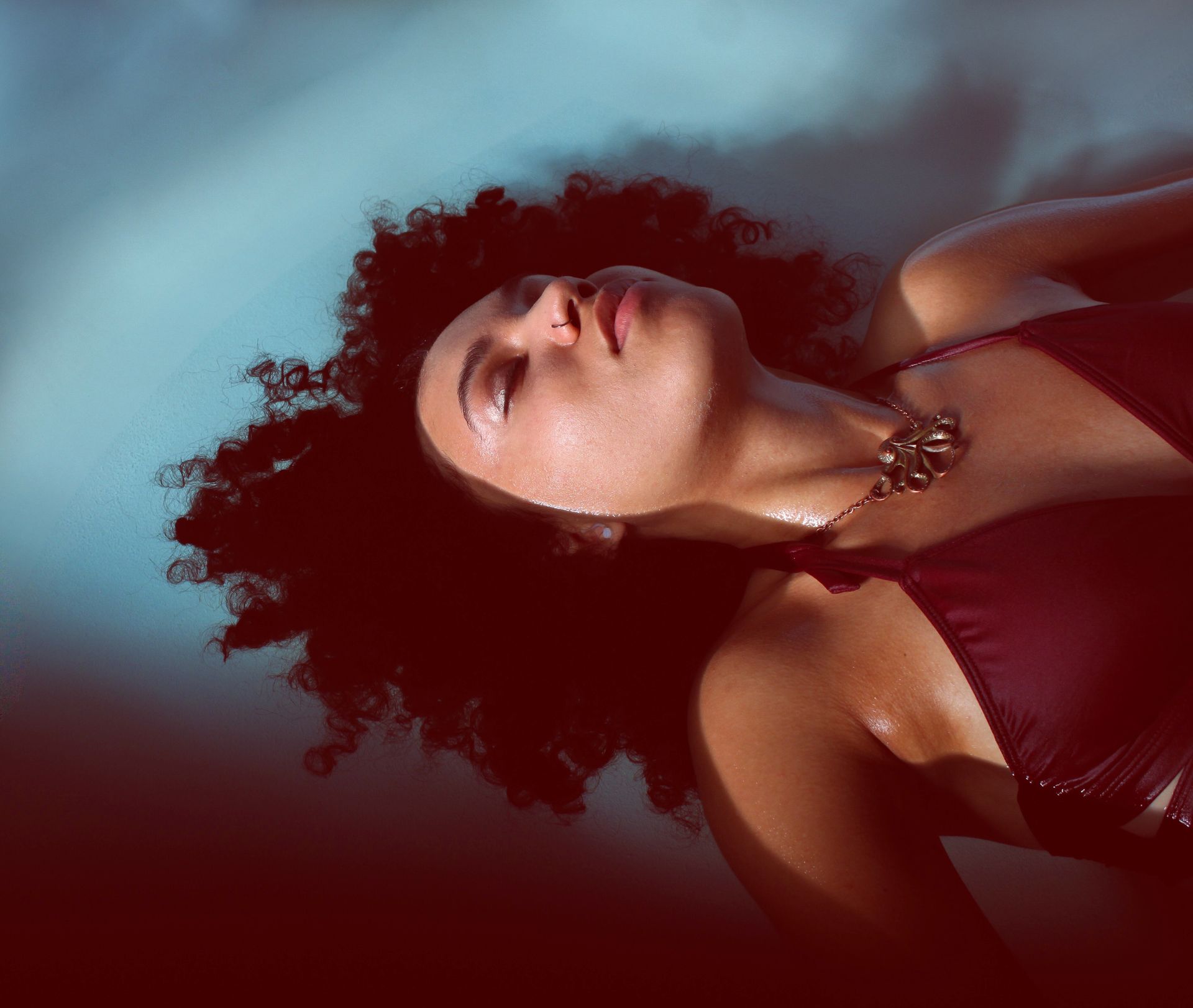 A woman with curly hair is laying down with her eyes closed