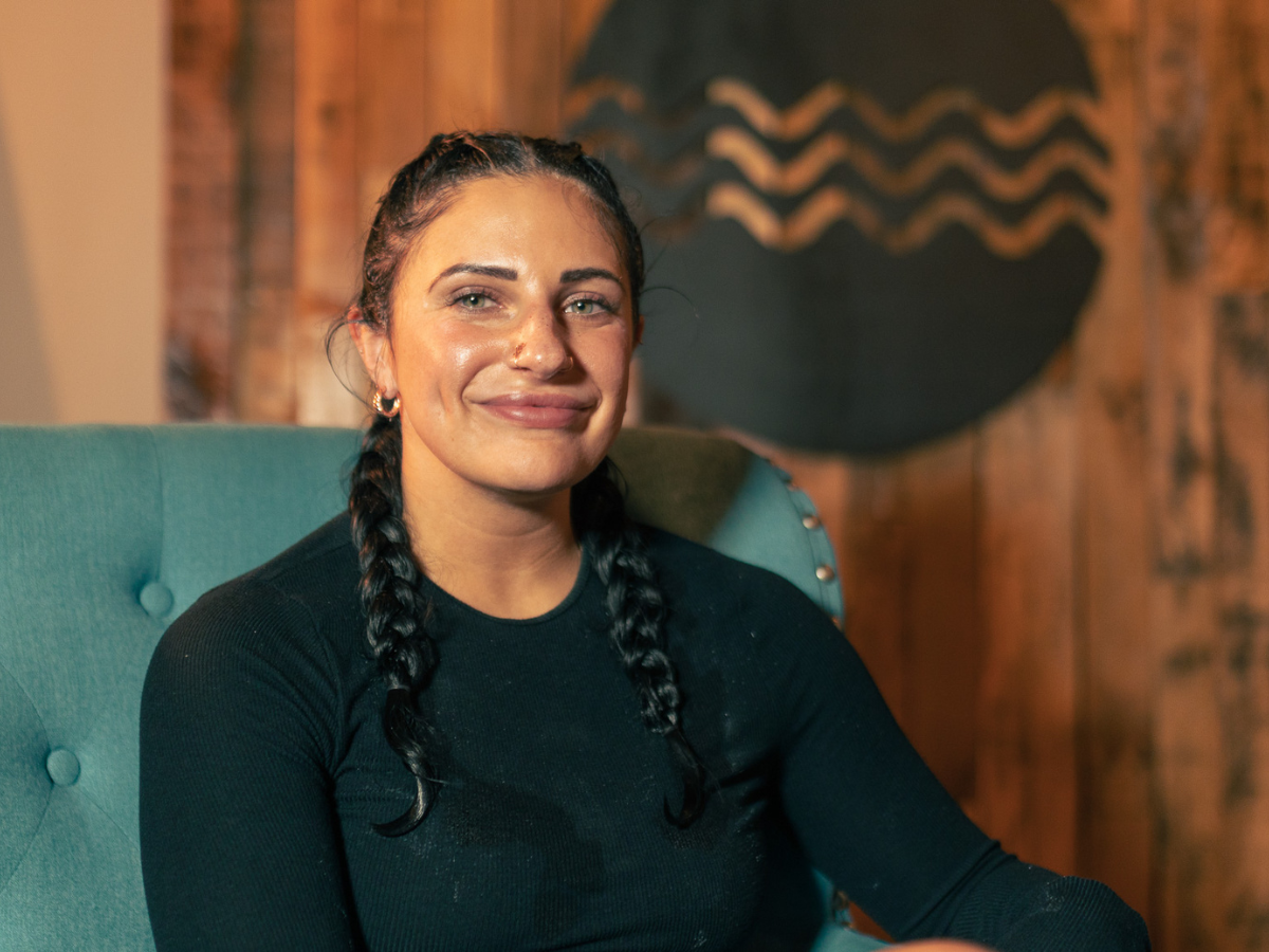 A woman is sitting in a chair and smiling for the camera.