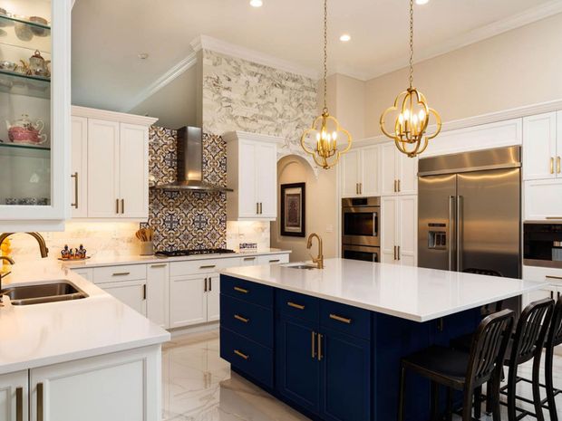 A kitchen with white cabinets , blue cabinets , and stainless steel appliances.