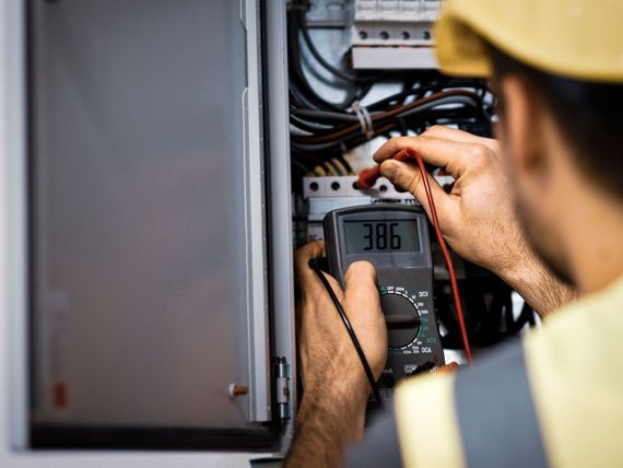 A man is using a multimeter to test a circuit board.