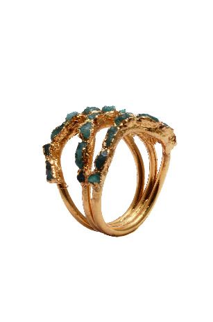 Un anillo de oro con piedras verdes sobre un fondo blanco.
