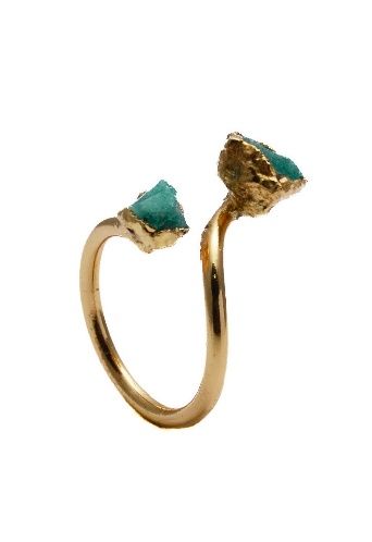 Un anillo de oro con dos piedras verdes sobre fondo blanco.