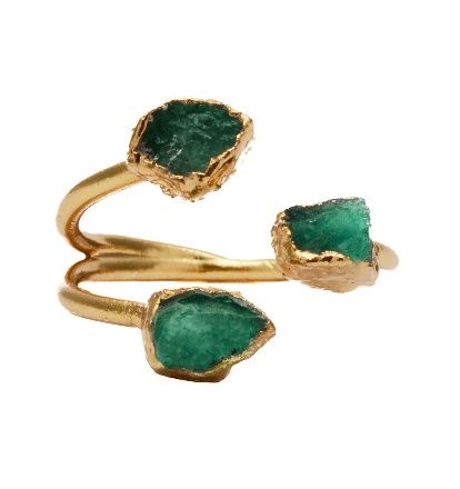Un anillo de oro con tres piedras verdes.