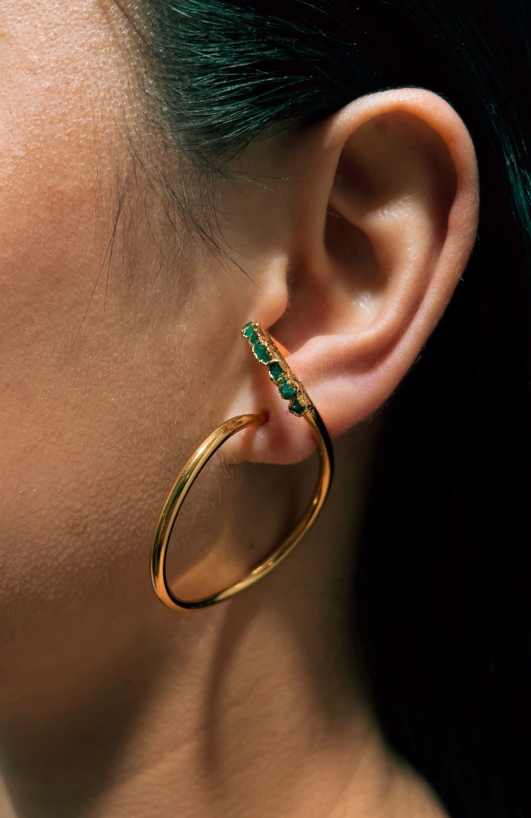 Un primer plano de la oreja de una mujer con un par de pendientes de aro.