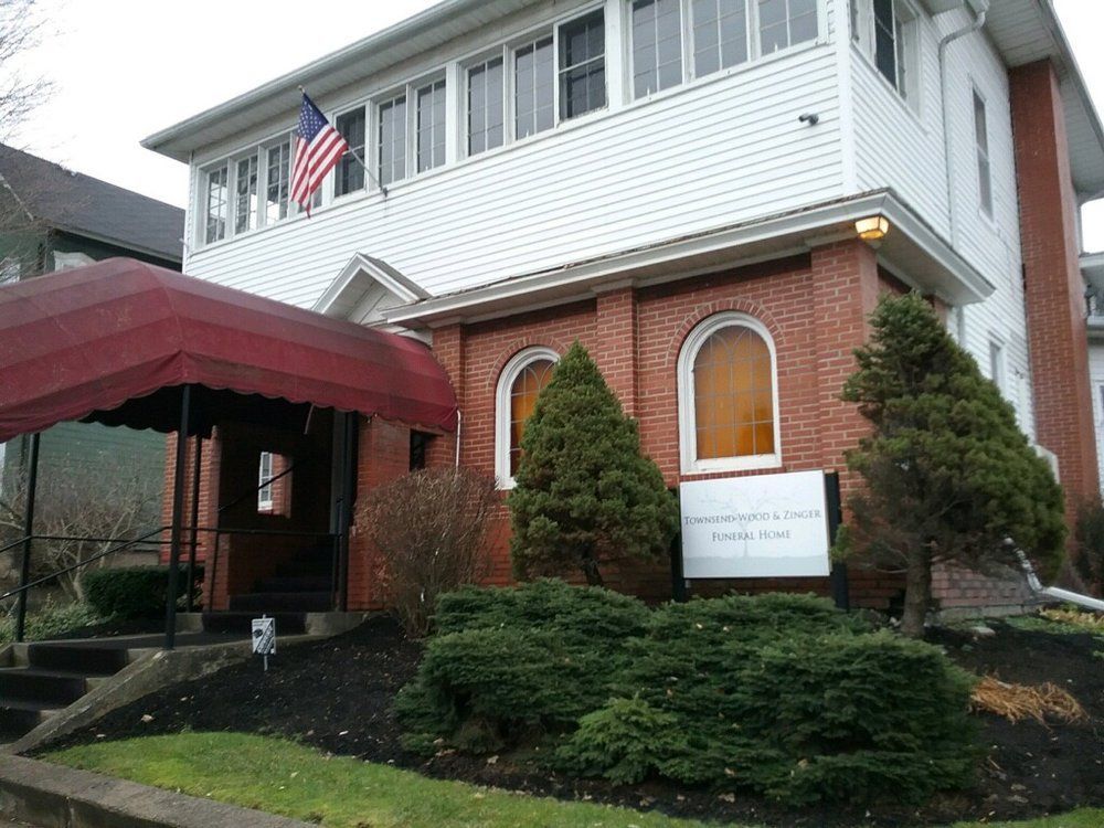 Exterior of brick and white building with US flag; awning over entrance; sign for Funeral Home.