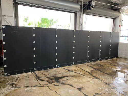 A large black wall is sitting in a garage next to a garage door.