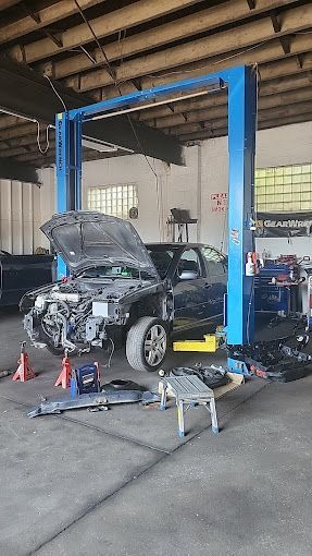 A car is sitting on a lift in a garage with the hood open.