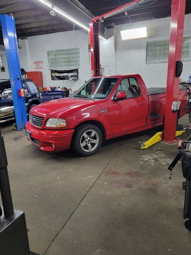 A red truck is parked on a lift in a garage.