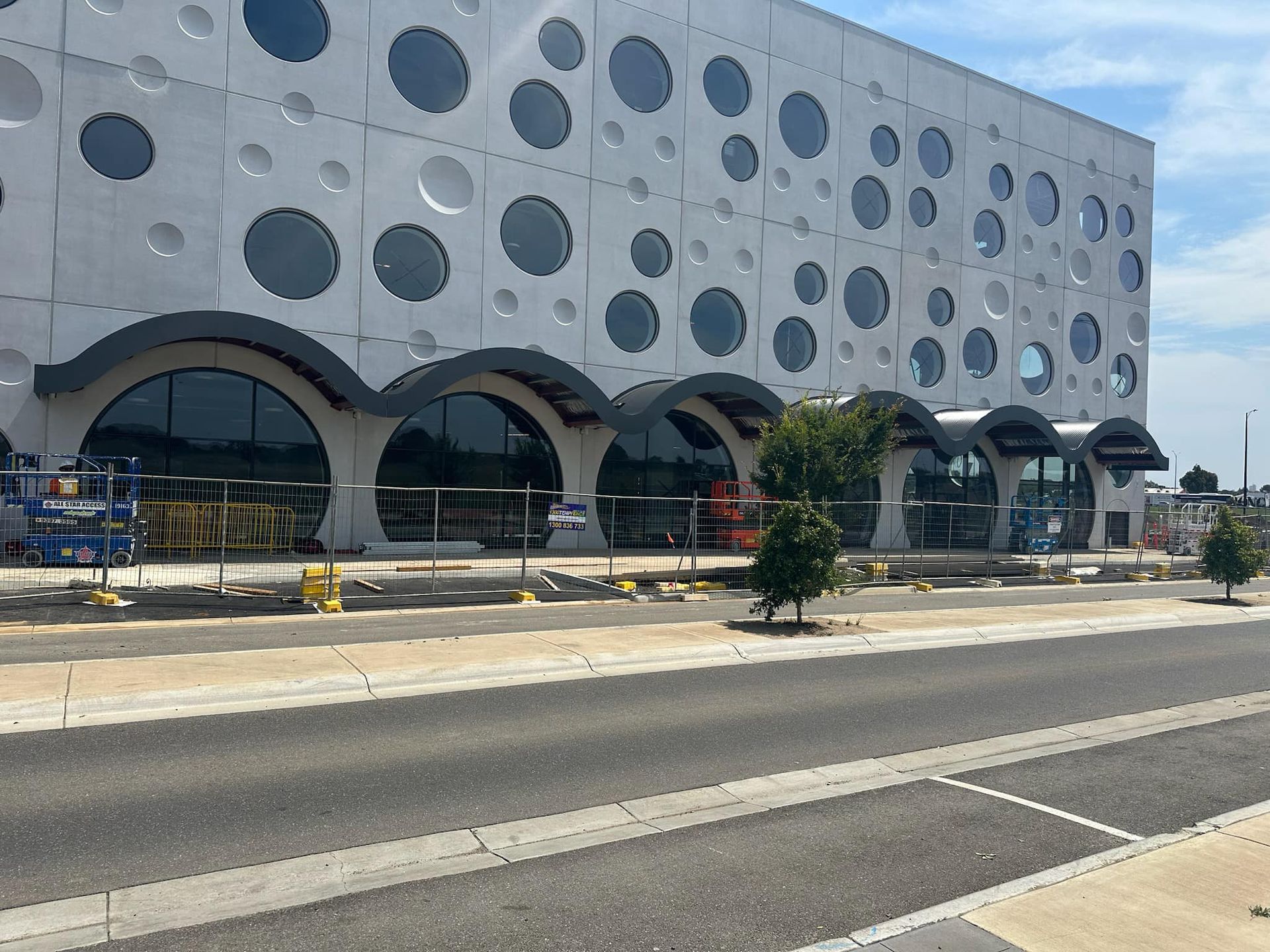 A large building with a lot of windows is being built next to a road.
