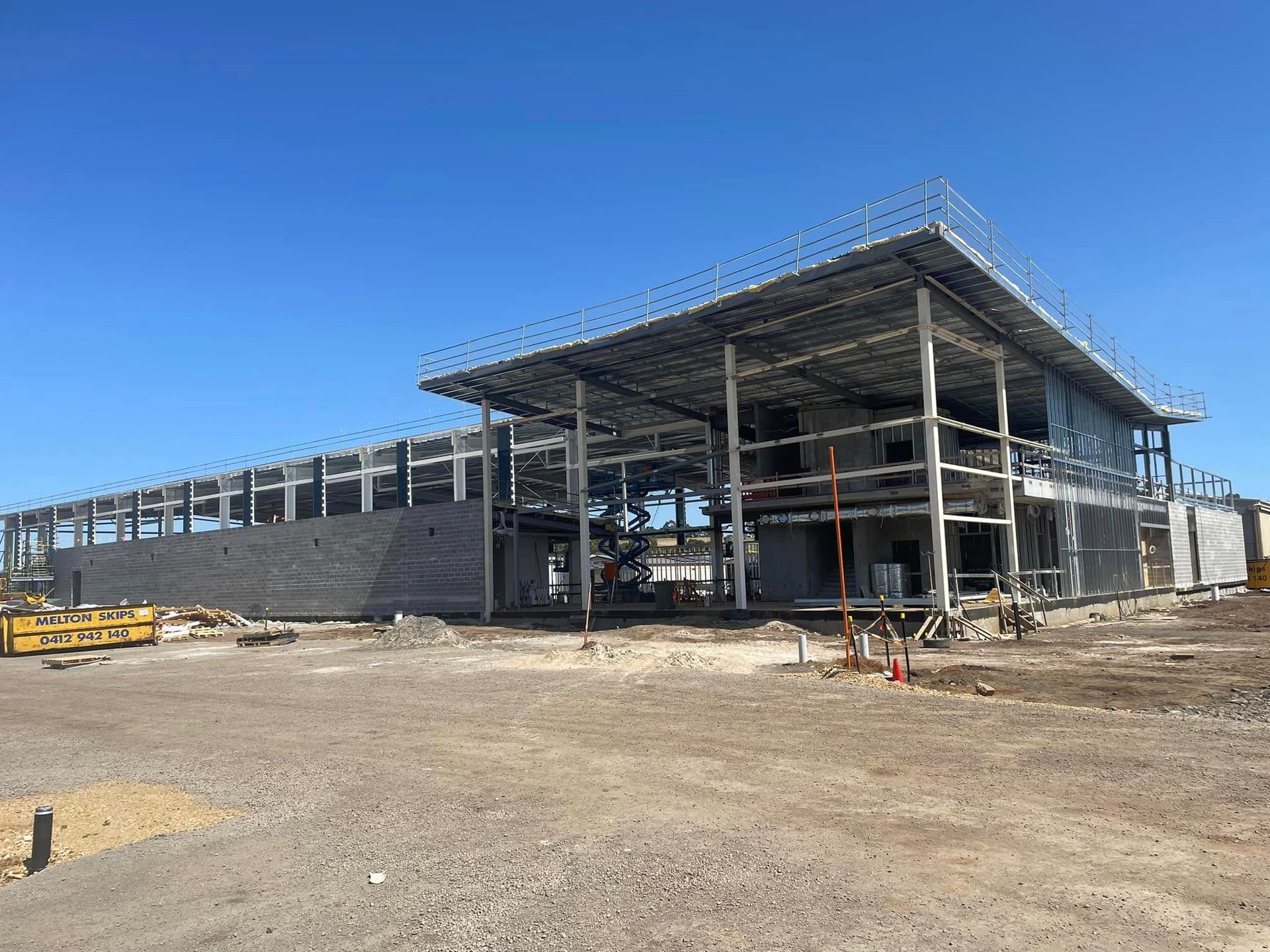 A large building is being built in the middle of a dirt field.