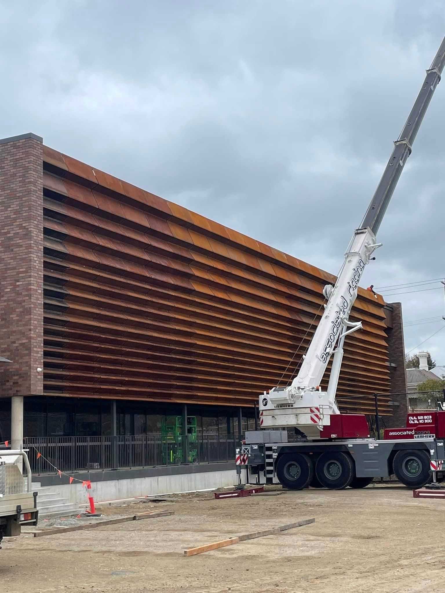 A large crane is sitting in front of a building under construction.