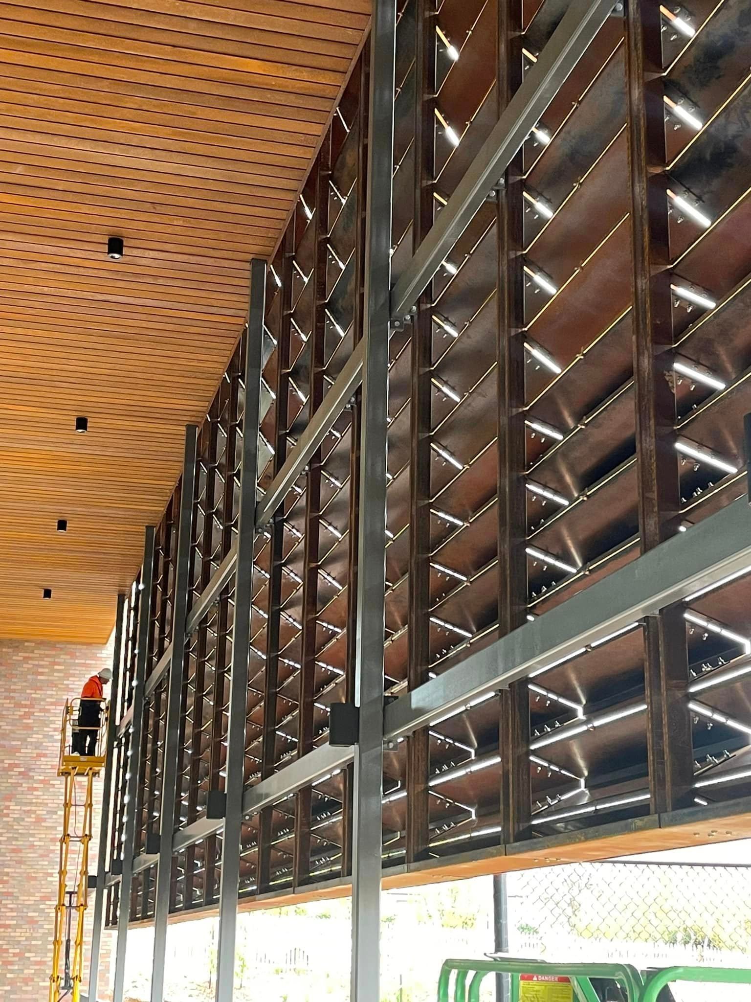 A man is standing on a ladder in front of a building under construction.