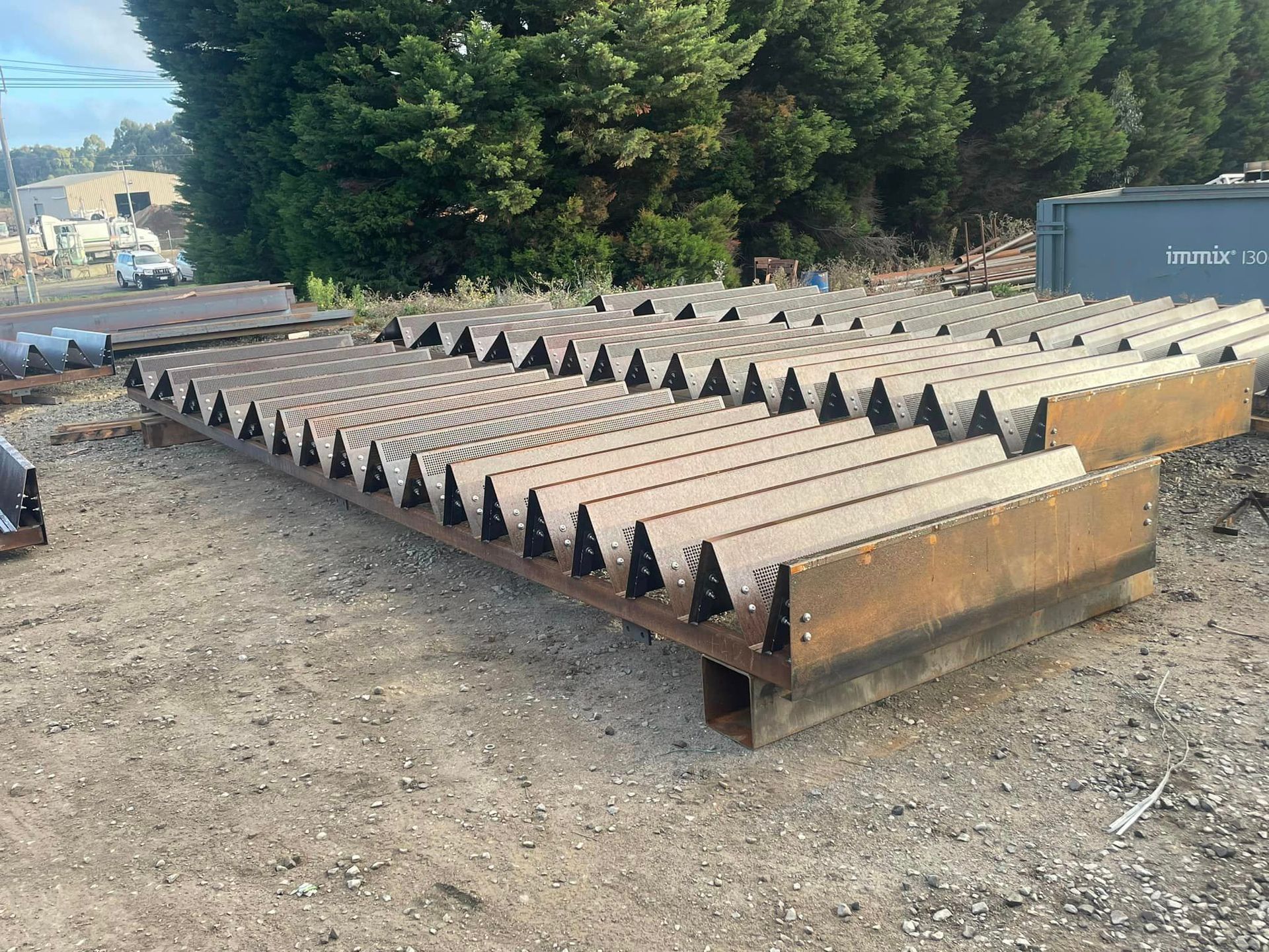 A large metal structure is sitting on top of a dirt field.