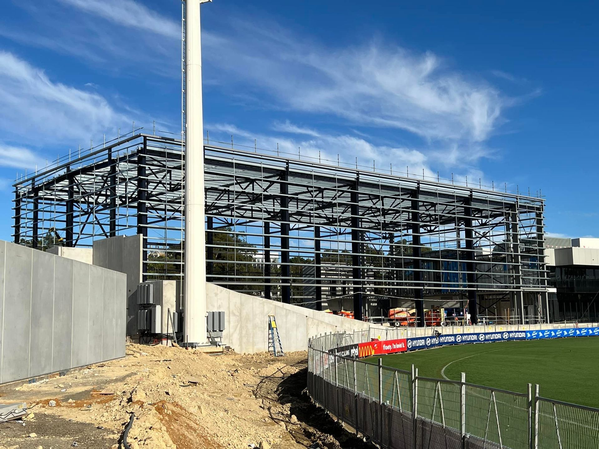 A large building under construction with a stadium in the background.