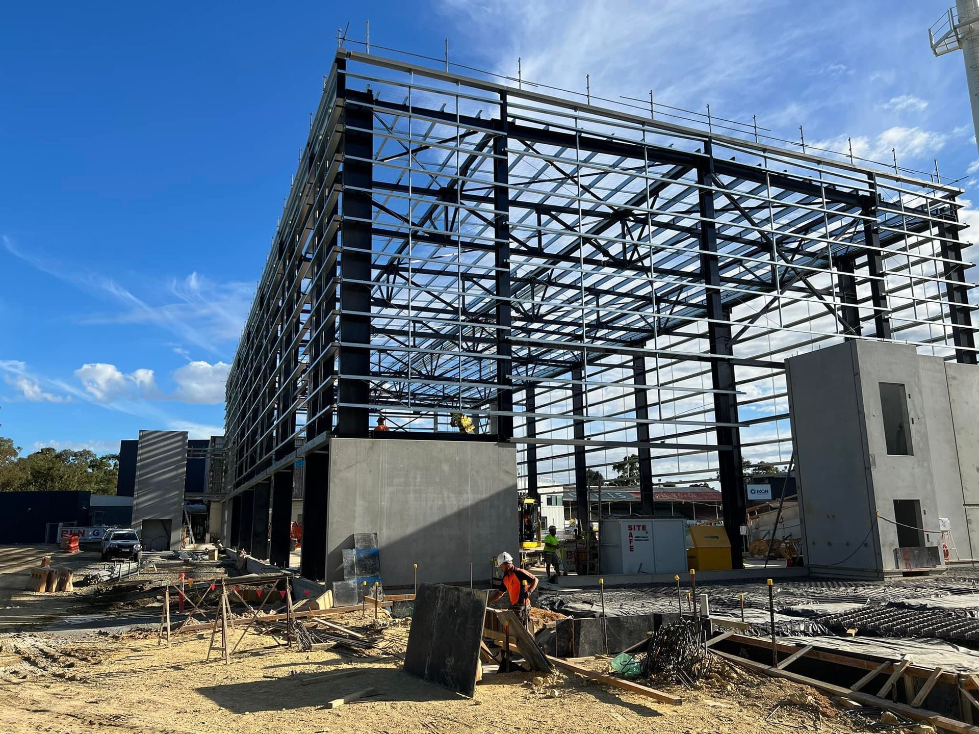 A large building is being built in the middle of a dirt field.