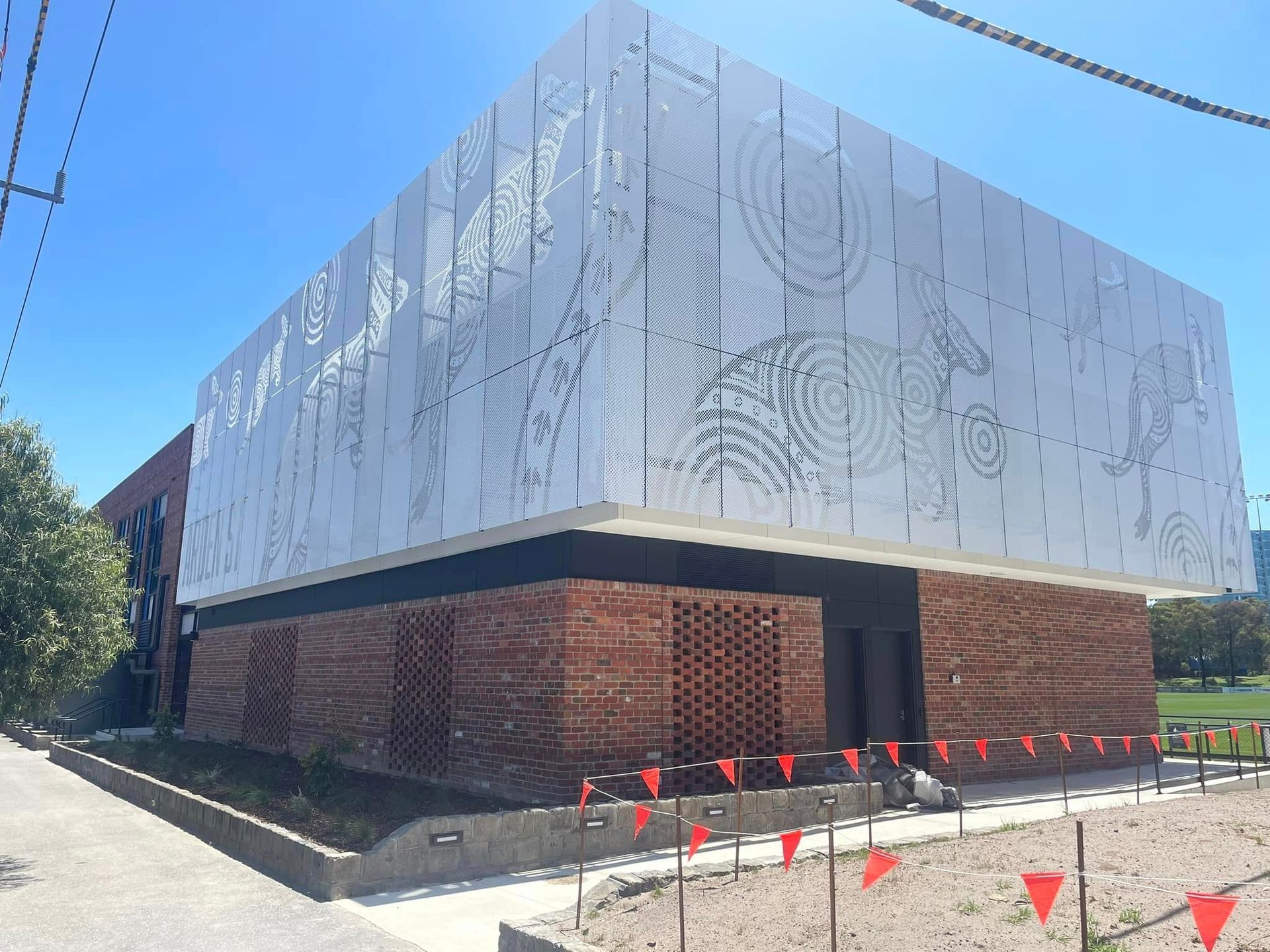 A large white building with a brick facade is surrounded by red flags.