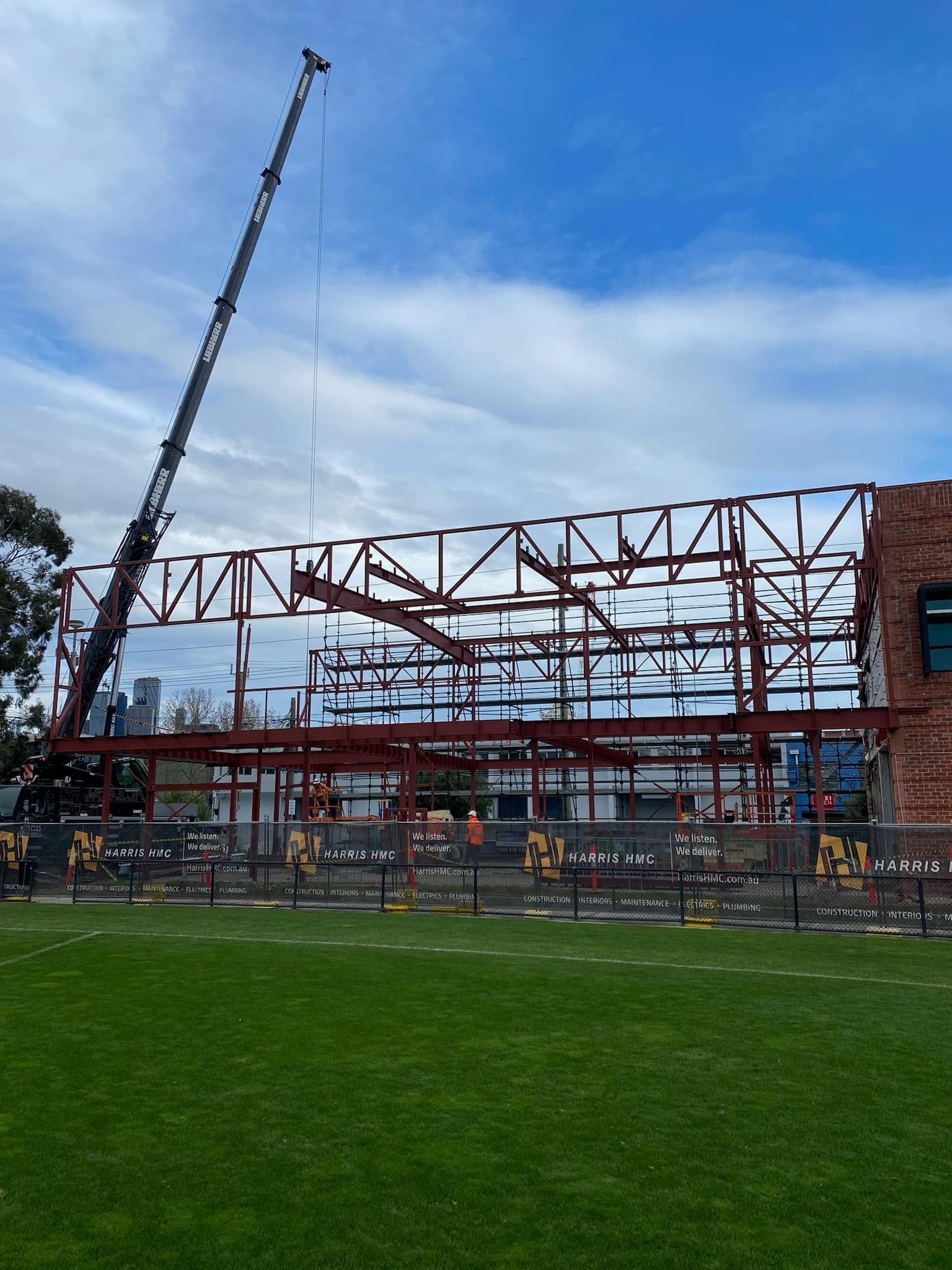 A crane is lifting a metal structure in a field.