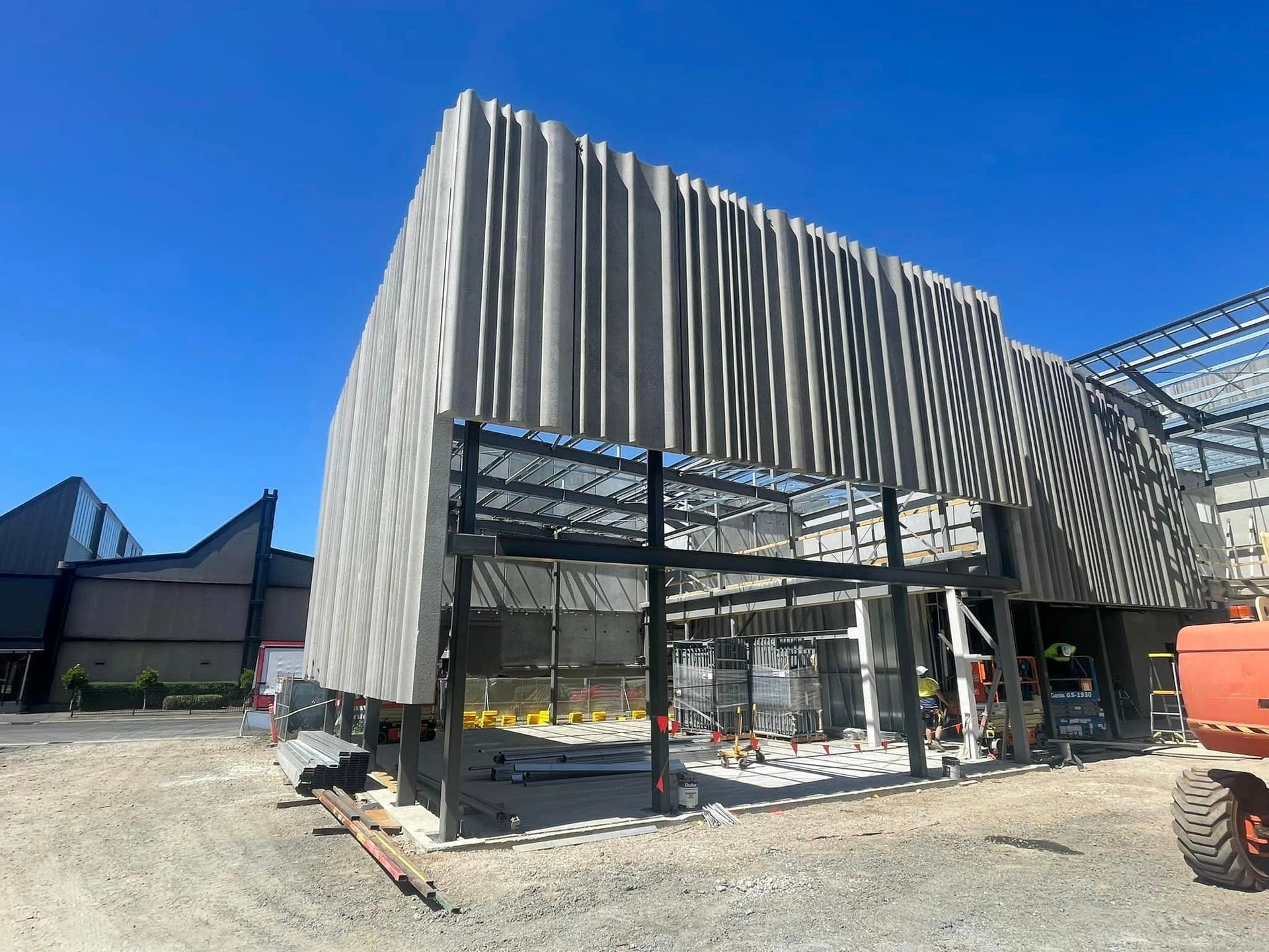 A large building under construction with a tractor parked in front of it.