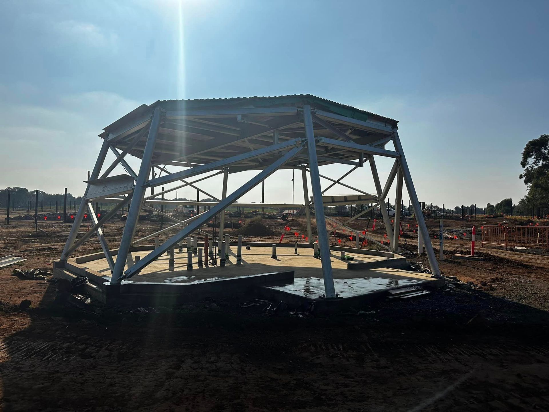 A large metal structure is sitting in the middle of a dirt field.