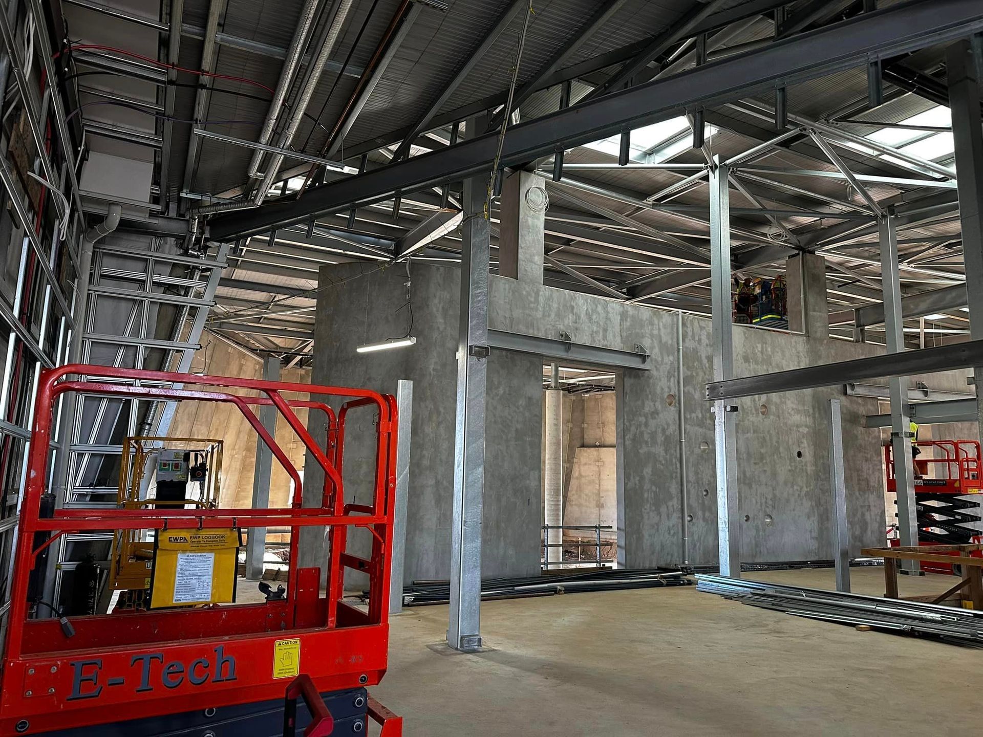 A red e-tech lift is in the middle of a building under construction